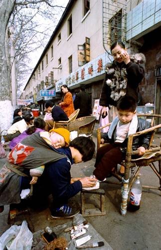 “穷母亲背着孩子给富孩子擦鞋”(资料图片)